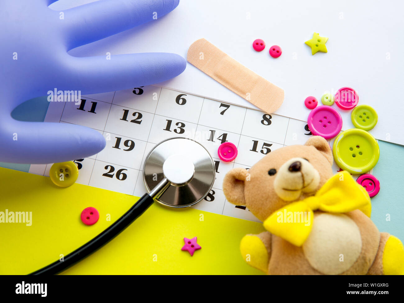 Children`s doctor appointment date number concept. Calendar with numbers, doctor, kids toys, pink and green buttons. Flat lay view. Stock Photo